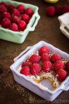 there are raspberries and other desserts in the dishes on the table together