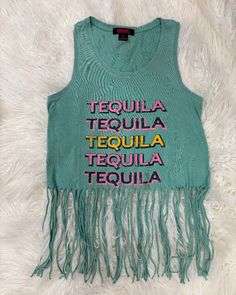 This Rock & Roll Aqua Tequila Western Graphic Fringe Sleeveless Tank is made from 100% cotton and features a scoop neck and shorter length, complete with trendy fringe detailing. Party Fringe Sleeveless Tank Top, Bohemian Fringe Sleeveless Tank Top, Disco Cowgirl Party T-shirts & Tank Tops, Beach Crop Top With Fringe Detail, Western Tank Tops, Western Wear T-shirts & Tank Tops, Trendy Fringe, Fringe Tank Top, Western Hats