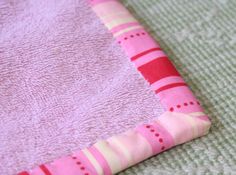 a pink and white blanket laying on top of a bed