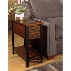 a brown couch with a wooden end table on top of it next to a chair