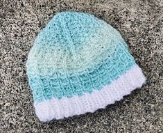 a blue and white knitted hat laying on the ground