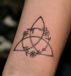 a tattoo on the arm of a woman with flowers and triangles around her wrist,