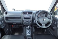 the interior of a small car with black leather seats and dashboard controls, including steering wheel