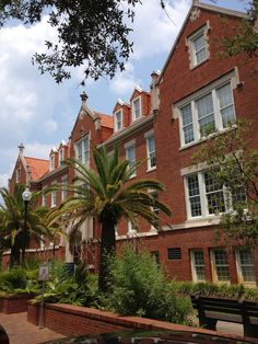 a brick building with palm trees in the foreground