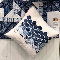 a blue and white quilted pillow hanging on the wall next to a pair of scissors