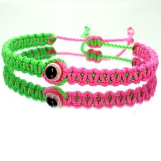 three bracelets with pink, green and black beads on white table top next to each other