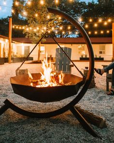 a fire pit sitting in the middle of a yard with string lights strung across it