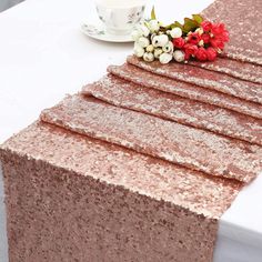 the table is covered with pink sequins and flowers next to a coffee cup