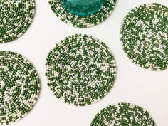 four green and white coasters sitting on top of a table next to a vase