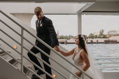 the bride and groom are walking down the stairs on their wedding day, holding hands