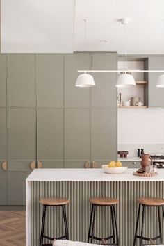 three stools sit at the bar in this modern kitchen with green cabinets and white countertops