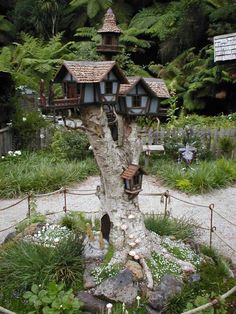 a tree house built into the side of a tree in a garden with lots of plants