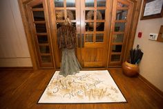 a woman standing in front of a wooden door with an area rug on the floor