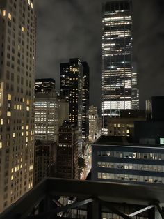 the city skyline is lit up at night, with skyscrapers in the foreground