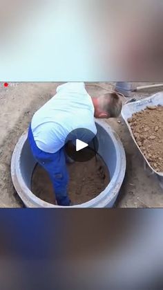 a man in white shirt and blue pants pouring cement into a large bucket on the ground