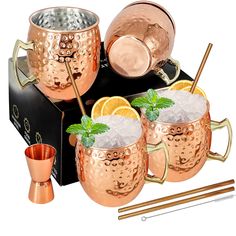 three copper mugs with ice and mint garnishes on a black box