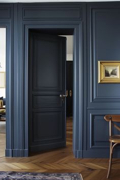 an empty room with blue walls and wooden flooring is pictured in this image from the doorway