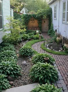 an outdoor garden with lots of plants and rocks in the center, surrounded by brick walkways