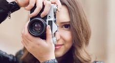 a woman is holding up a camera to take a selfie with her hand and smiling