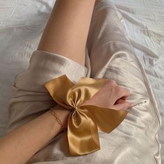 a woman laying on top of a bed with her legs wrapped in gold satin material