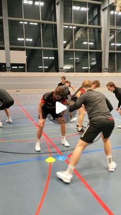 a group of young men playing a game of frisbee on an indoor court