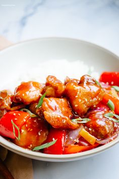 a white bowl filled with chicken and vegetables on top of rice next to chopsticks