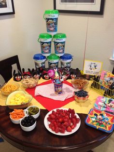 a table topped with bowls of fruit and snacks