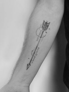 a black and white photo of a person's arm with an arrow tattoo on it