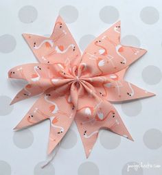 an orange bow with flamingos on it sitting on top of a polka dot surface