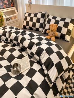 a black and white checkered comforter set with a teddy bear sitting on it