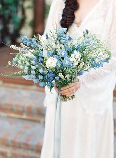 a woman holding a bouquet of blue and white flowers