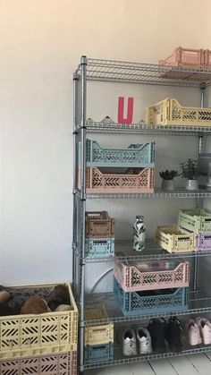 a metal shelving unit with baskets and shoes on the bottom shelf next to it