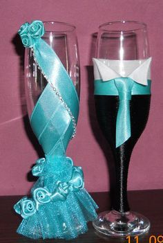 two wine glasses decorated with blue ribbons and bows are sitting next to each other on a table