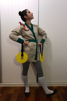 a woman standing in front of a white wall with two yellow circles attached to her waist