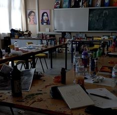 an empty classroom with desks and paintings on the walls