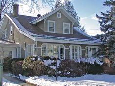 a house with snow on the ground in front of it and trees behind it,