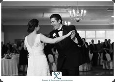 a bride and groom dancing at their wedding reception in black and white photo with chandelier