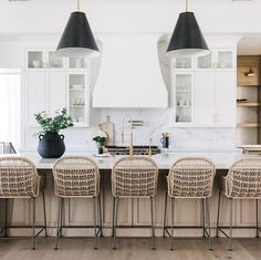 a kitchen with white cabinets and wicker bar stools