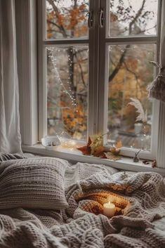 a bed with blankets and candles on top of it next to a window sill