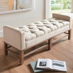 an open book sitting on top of a wooden floor next to a bench and window