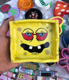 a hand holding a yellow square plate with an image of a spongebob face on it