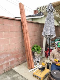 a man is sitting on the ground working on some construction equipment in front of a brick wall