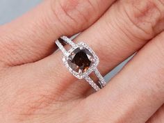 a woman's hand with a brown and white diamond ring on top of it