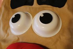 two white plates with eyes on them sitting on a brown cloth covered tablecloth next to a pair of black eyeballs