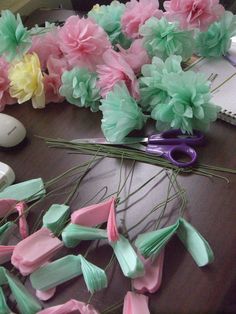 pink, green and yellow flowers are on the table next to a pair of scissors