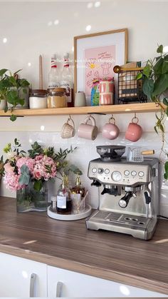 a coffee maker sitting on top of a counter next to potted plants and flowers