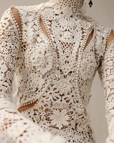 the back of a woman's white dress with crocheted lace on it