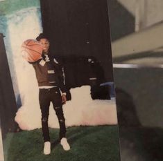 a man holding a basketball in his right hand and standing next to a painting on the wall