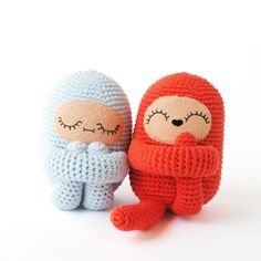 two knitted dolls sitting next to each other on a white surface with eyes closed