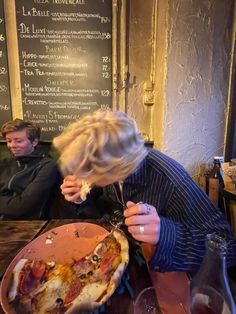 a woman is eating pizza at a restaurant